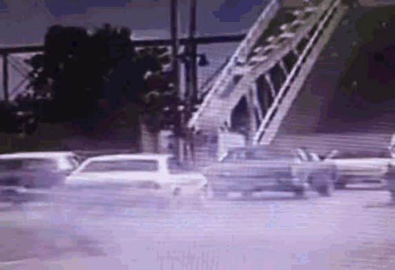 a blurred image of cars driving down a road with a bridge in the background
