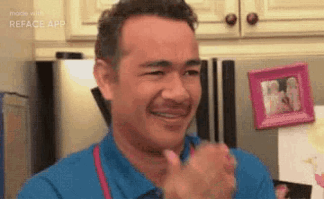 a man with a mustache is smiling and clapping in front of a refrigerator .