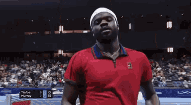 a man in a red shirt is standing on a tennis court .