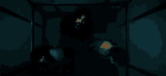 three people are standing in an elevator looking up at the camera .
