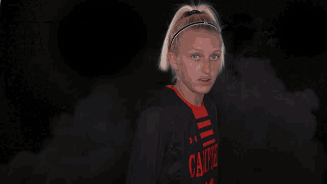 a girl in a campbell jersey stands in front of a smokey background