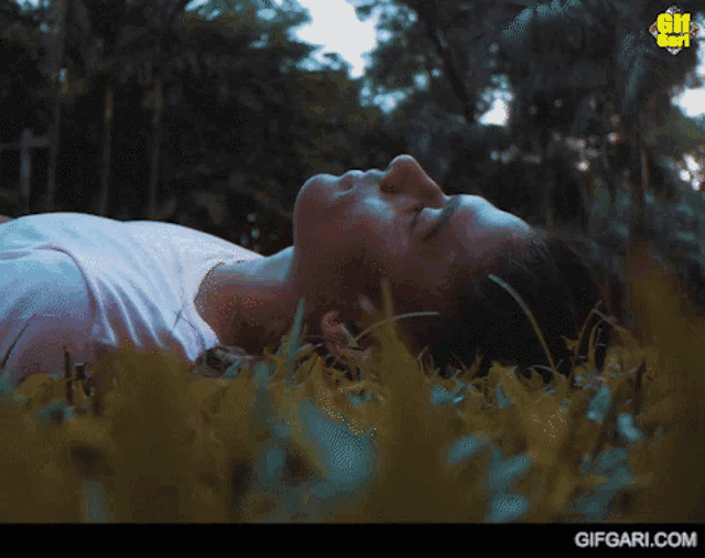 a woman laying in the grass with gifgari.com written on the bottom