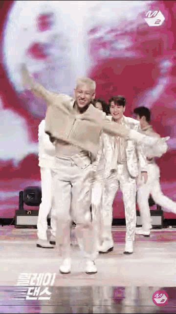 a group of young men are dancing on a stage with a sign that says m.