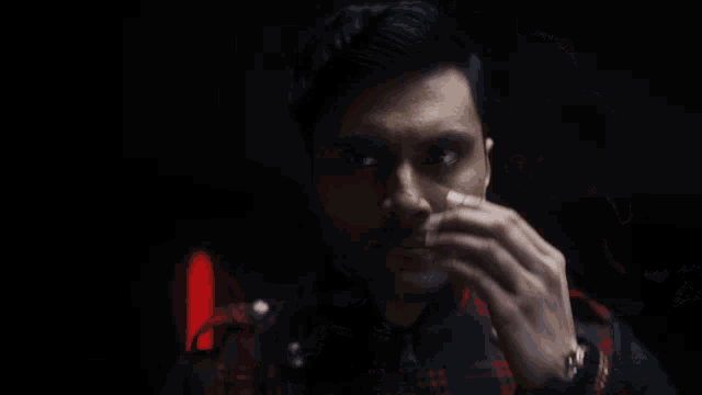 a man talking on a cell phone with a red light behind him