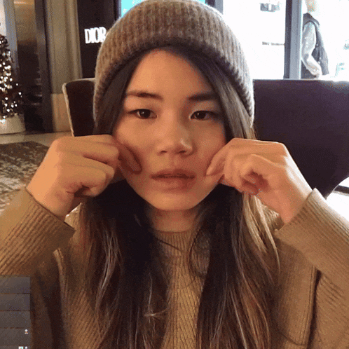 a woman wearing a beanie is making a funny face