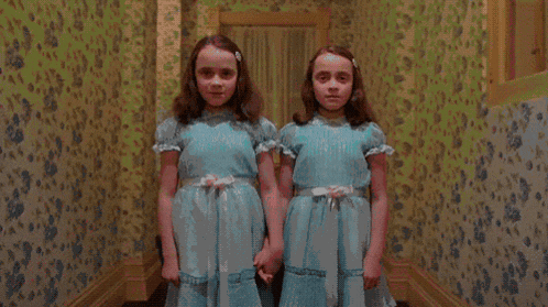 two young girls in blue dresses are holding hands in a hallway