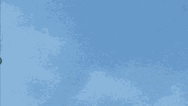 a gray object is flying in the sky with the letter i on it