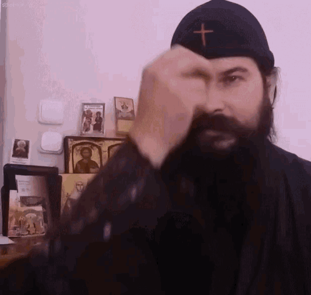 a man with a beard is wearing a black hat with a cross on it .