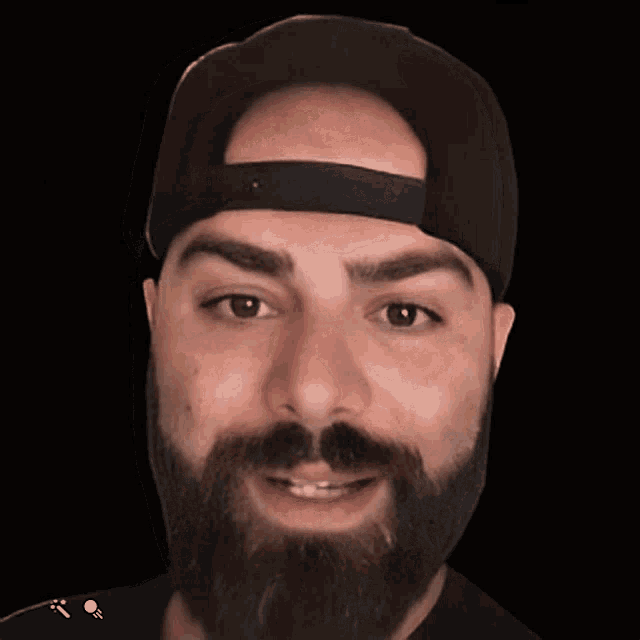 a man with a beard is wearing a black hat and smiling