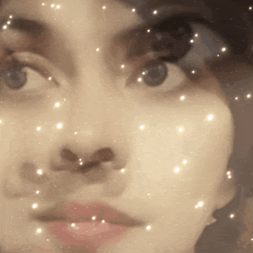 a close up of a woman 's face with sparkles around it