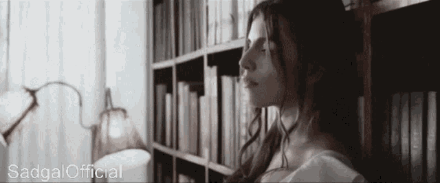 a woman is standing in front of a bookshelf with the words sadgal official written on the bottom
