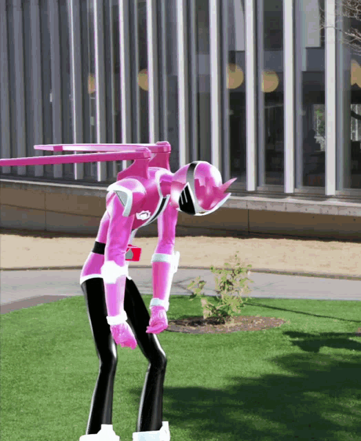 a pink robot with a sword on its back is standing on the grass