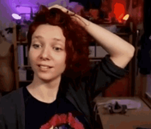 a woman with red hair is holding her hair in her hands .