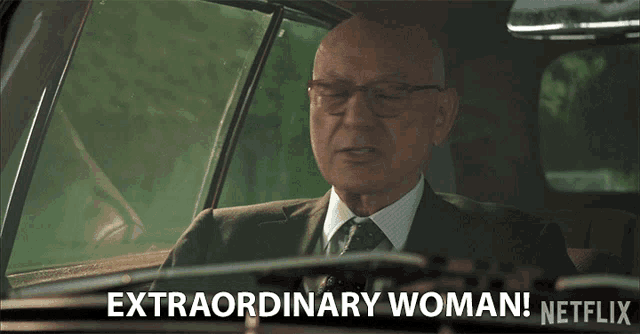 a man in a suit and tie is driving a car and says " extraordinary woman " on the bottom
