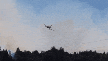a plane is flying over a forest and spraying water