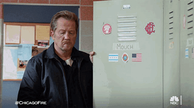 a man is standing in front of a locker that says mouch on it