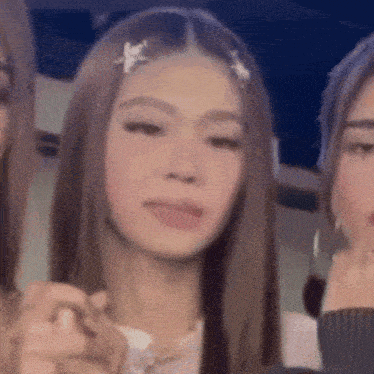 a close up of a woman 's face with two other women standing next to her .