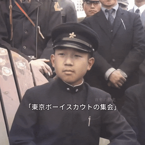 a boy in a military uniform stands in front of a group of men in suits and tie
