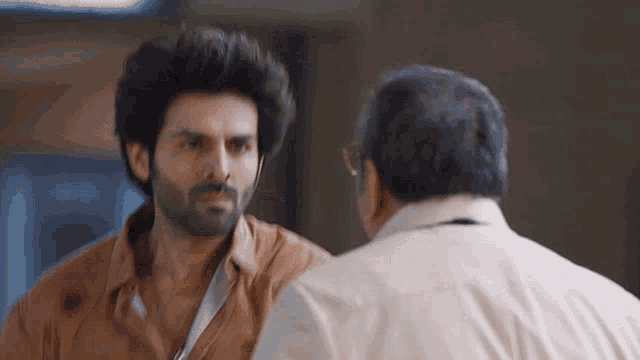 two men are talking to each other in a room .