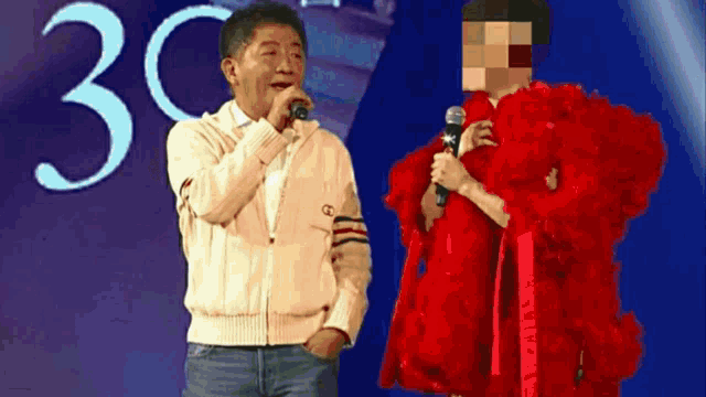 a man singing into a microphone next to a woman in a red dress with the number 30 in the background
