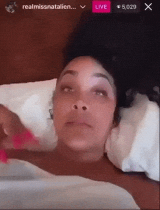 a woman is laying in a bed with a live button visible
