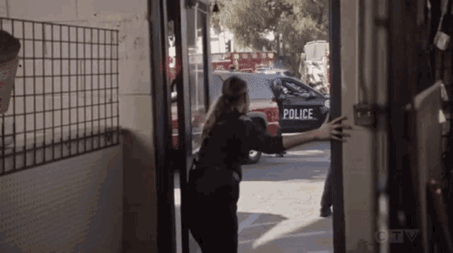 a police officer is trying to open a door to a police car .
