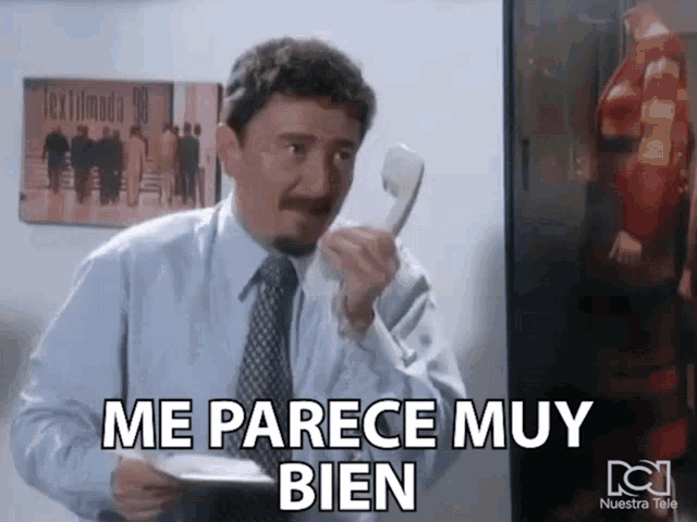 a man in a suit and tie is talking on a phone and the words me parece muy bien are above him