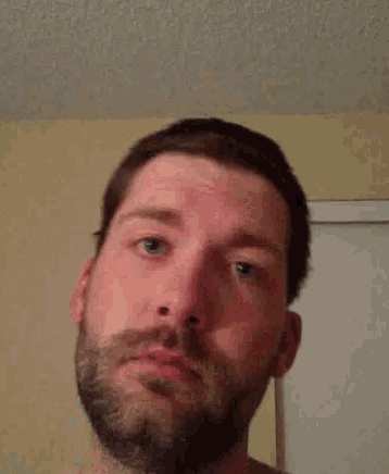 a man with a beard is looking at the camera with a serious look on his face .