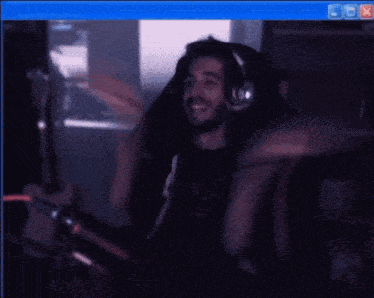 a man wearing headphones is smiling in front of a computer monitor