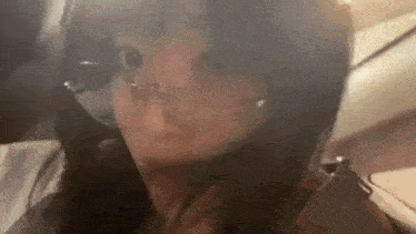 a woman is making a funny face while sitting in the back seat of a plane .