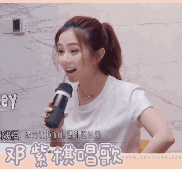 a woman holding a microphone in front of a sign that says key