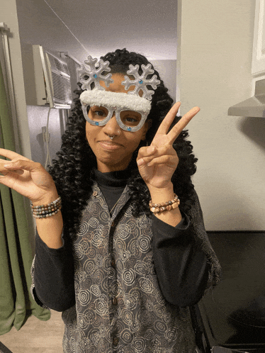 a woman wearing snowflake glasses gives a peace sign