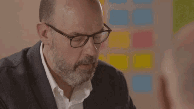 a man with glasses and a beard is looking down