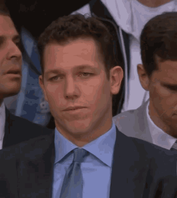 a man in a suit and tie stands in a crowd of people