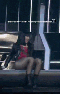 a woman in a leather jacket sits on a bench with her legs crossed ..