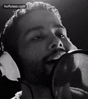 a man is singing into a microphone while wearing headphones .