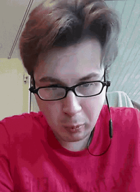 a man wearing glasses and headphones has a red shirt that says ' armani ' on it