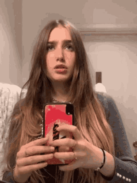 a woman is taking a selfie in front of a mirror with her cell phone .