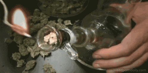 a person is smoking a marijuana pipe with a lighter in it .