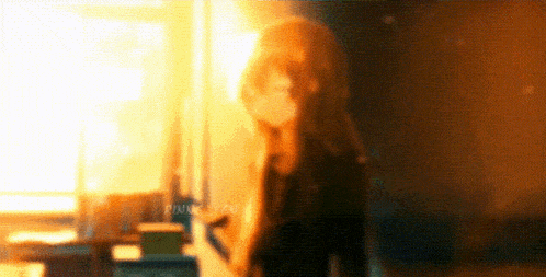 a blurry picture of a girl with long hair standing in front of a window .