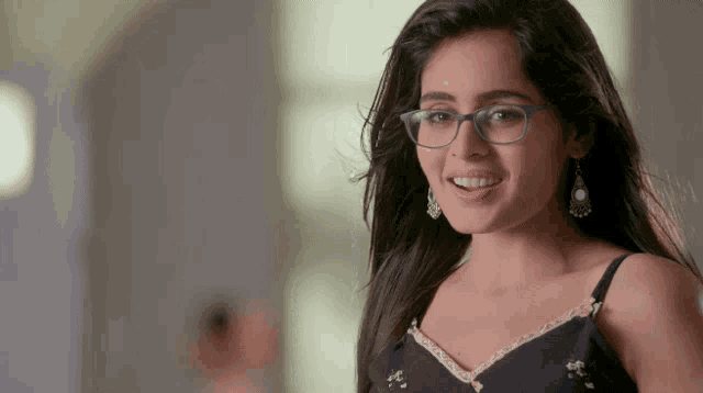 a woman wearing glasses and earrings is smiling for the camera