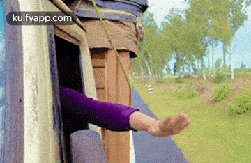 a person is sticking their hand out of a window while riding a train .