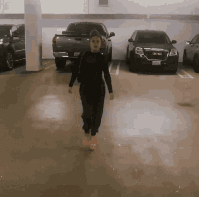 a woman is walking in a parking garage with a gmc truck parked behind her