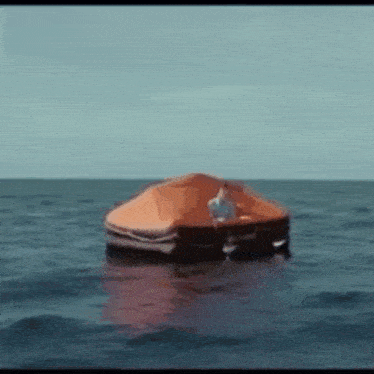 a man in a life preserver is floating in the ocean .