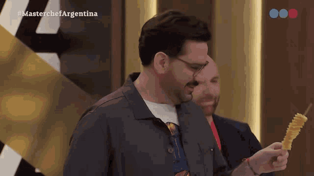 a man is holding a skewer in front of a masterchef argentina logo