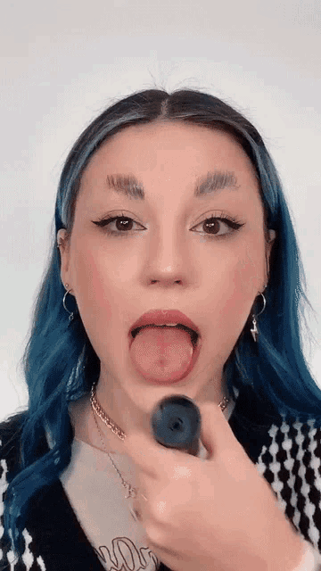 a woman with blue hair sticking out her tongue