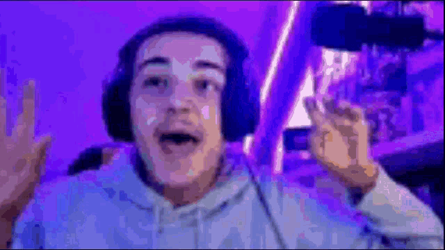 a man wearing headphones is making a funny face in a room with purple lights .