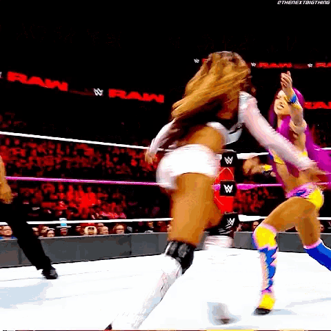two women are wrestling in a ring with a crowd watching and a sign that says raw