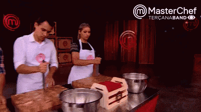 a man and a woman are standing at a table in front of a master chef sign