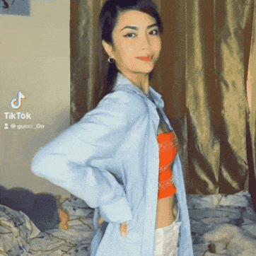 a woman in a blue shirt is standing in front of a tiktok icon
